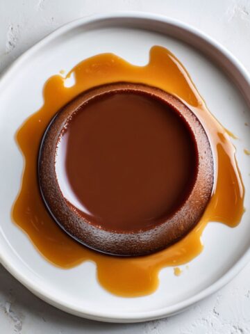 Unmolded homemade chocolate flan recipe with caramel sauce on white plate
