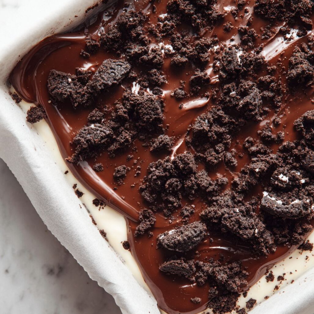 Chocolate topping being poured or spread over cream layer