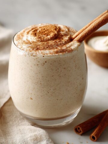 Cinnamon roll smoothie recipe served in a glass with a cinnamon stick beside it