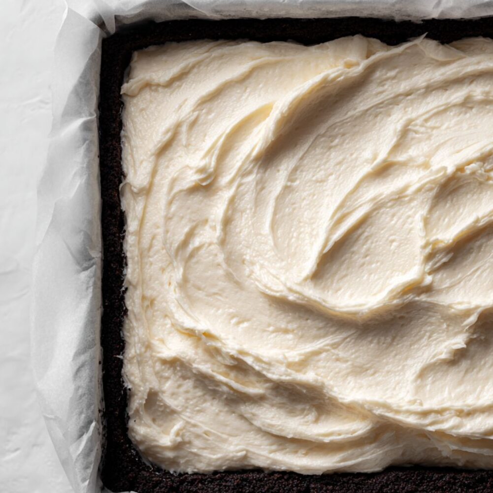 Cream cheese mixture being spread over Oreo crust in pan