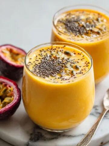 Passionfruit smoothie recipe served in a glass with fresh passion fruits on a white kitchen counter