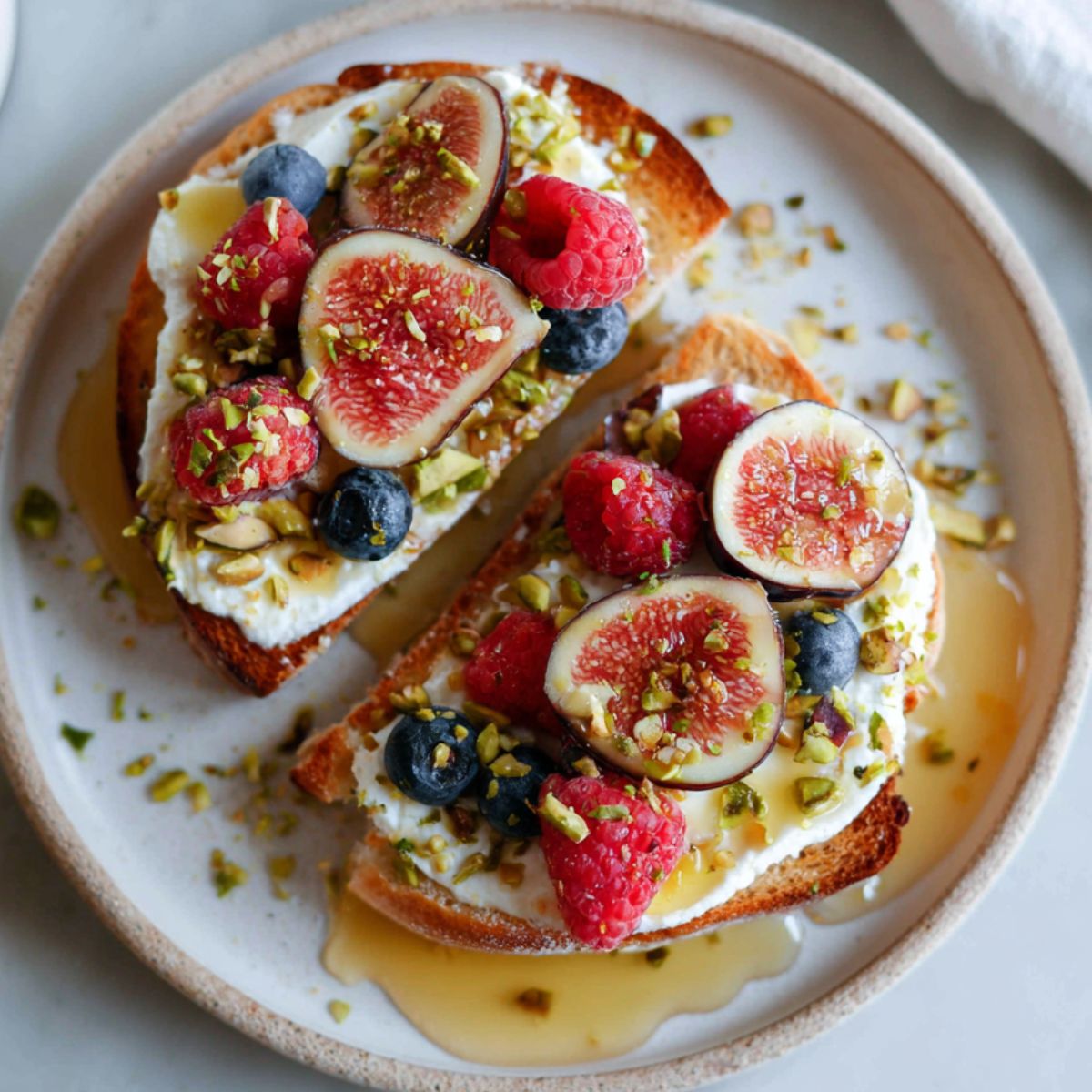 Ricotta and honey toast recipe on a plate topped with berries and nuts