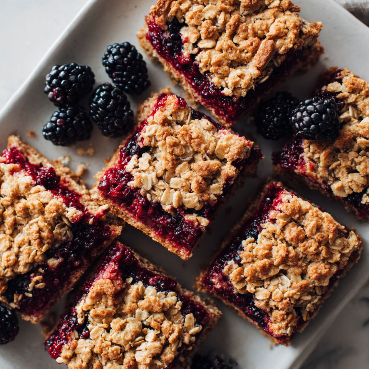 Freshly baked homemade blackberry oatmeal bars recipe on parchment with crumbly oat topping and juicy blackberry filling.