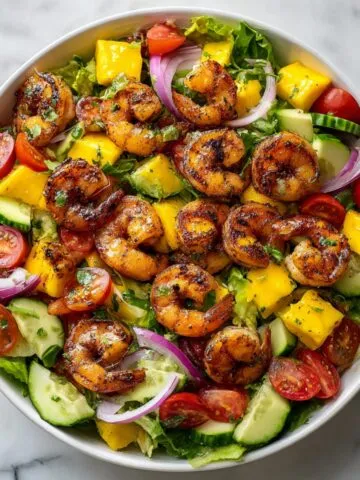 Overhead view of shrimp mango salad recipe with avocado, mango, shrimp, and citrus dressing in a white bowl