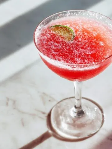 Homemade watermelon lime juice recipe in a clear glass on a white kitchen counter