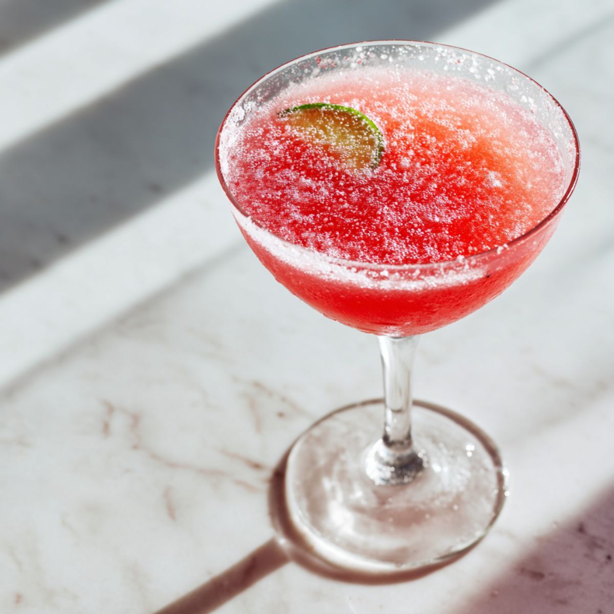 Homemade watermelon lime juice recipe in a clear glass on a white kitchen counter