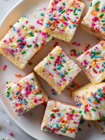 Homemade Funfetti cake bars recipe sliced on parchment paper with colorful sprinkles