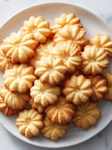 Homemade German spritz cookies recipe on a plate with rustic holiday decoration.