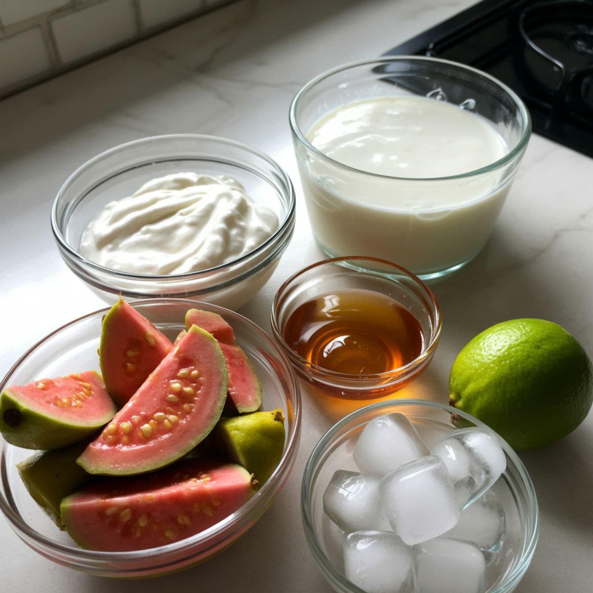 Chopped guava, yogurt, lime, coconut milk, and ice cubes arranged for smoothie

