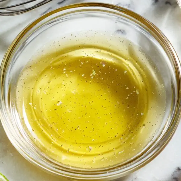 Mixing citrus dressing with lime, olive oil, and honey for shrimp mango salad
