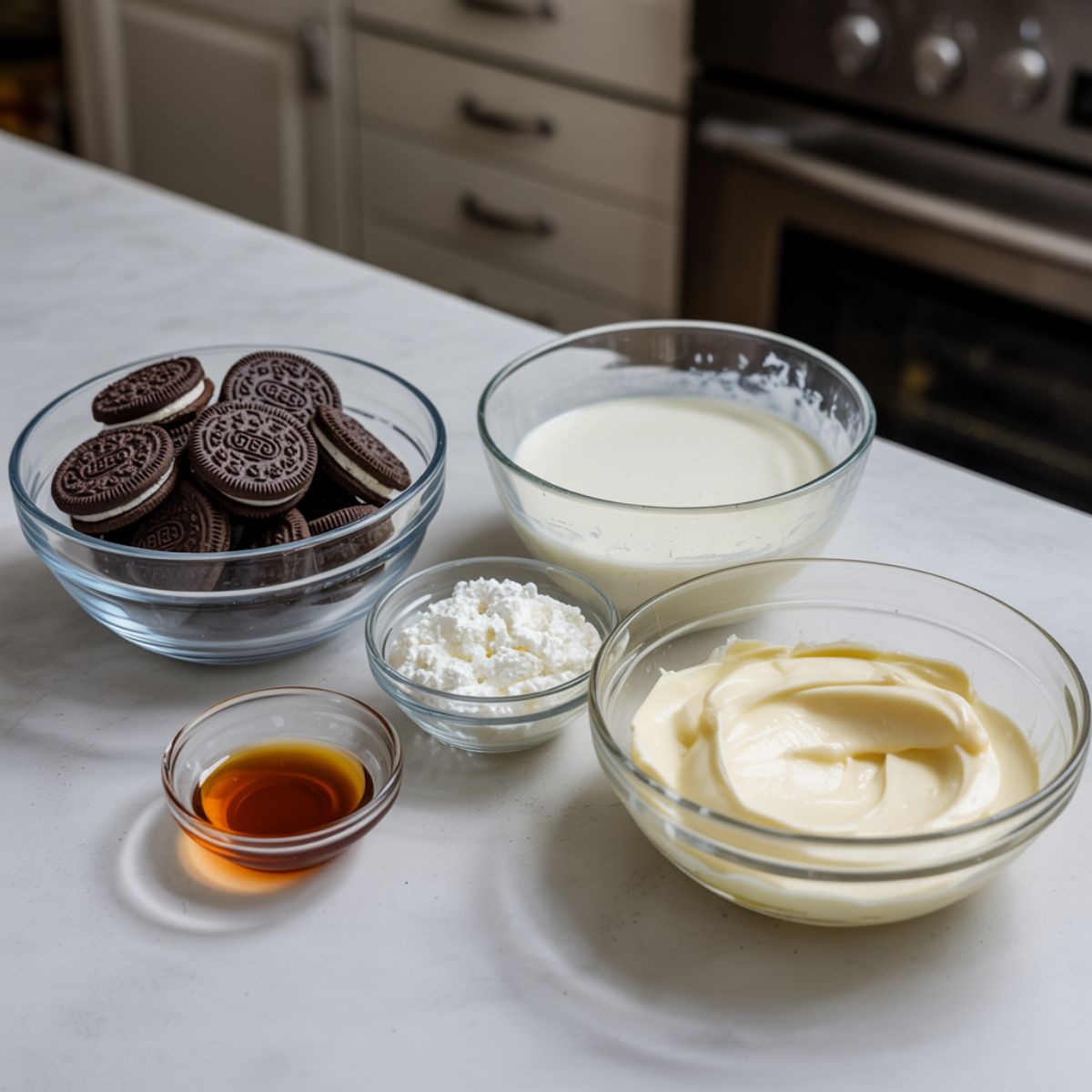 Close-up of ingredients for Oreo icebox cake laid out on a white kitchen counter