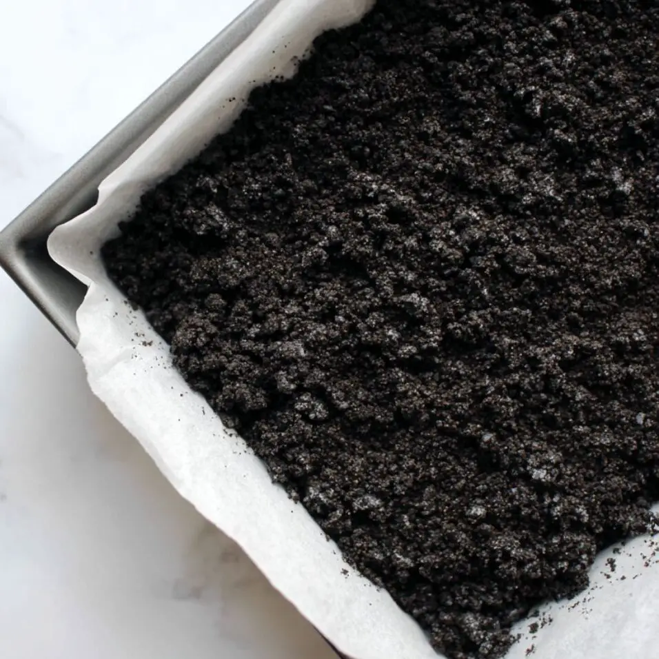 Crushed Oreo crust mixture pressed into a baking pan