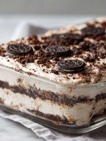 Overhead view of a chilled Oreo icebox cake recipe in a glass dish, topped with crushed Oreos