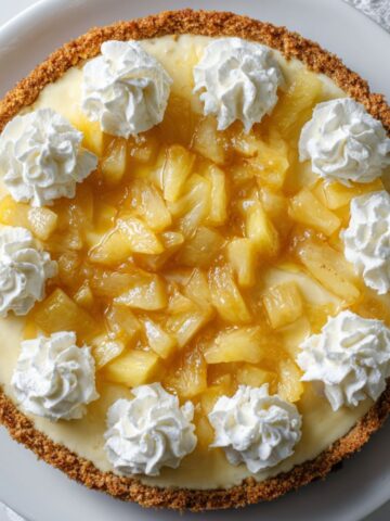 Pineapple cheesecake recipe with whipped topping and pineapple chunks on a white plate
