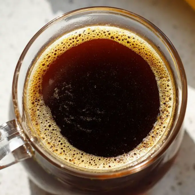 Freshly brewed coffee cooling beside a banana on a white kitchen counter