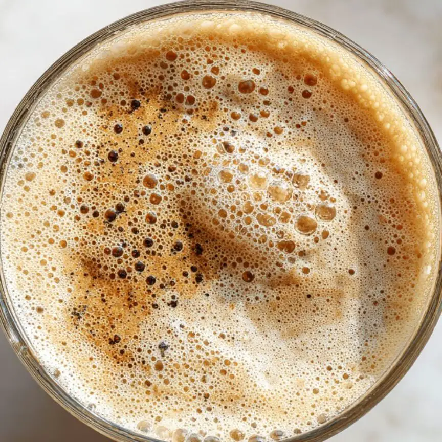 Served banana coffee smoothie in a clear glass with creamy texture