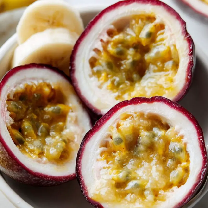 Scooping passion fruit pulp into a bowl beside banana slices