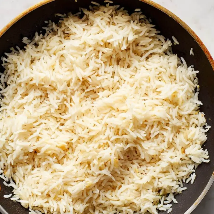 Toasting basmati rice and garlic in olive oil on a stovetop.