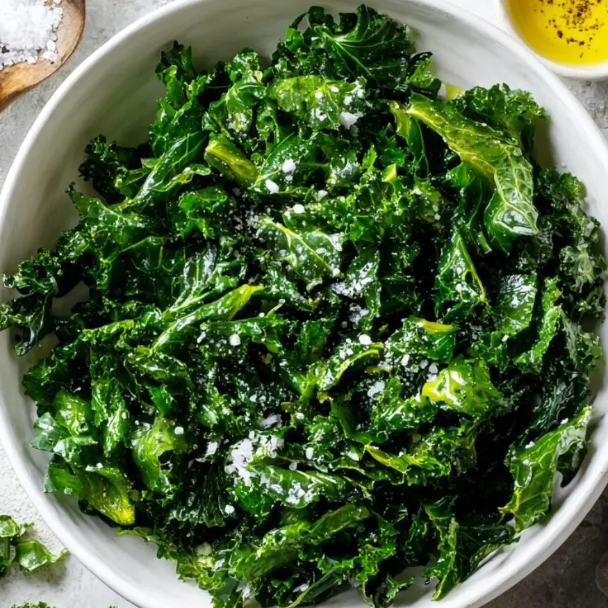 Chopped kale being massaged in a bowl with olive oil.