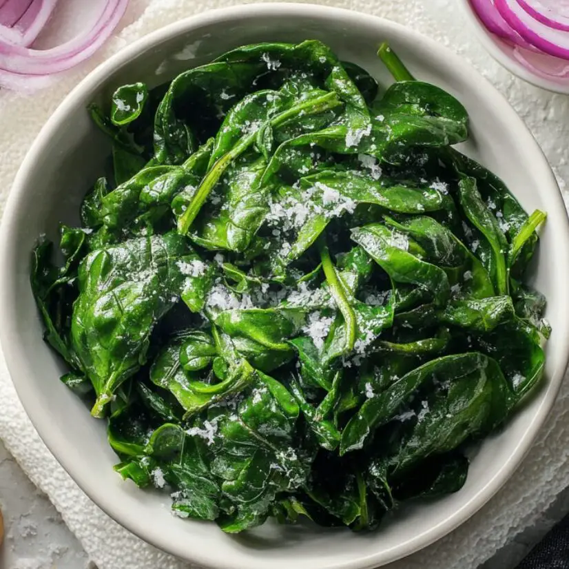 Spinach drying and other pizza toppings prepped on a kitchen counter