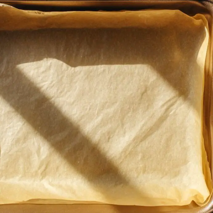 Baking pan lined with parchment and fresh sliced peaches ready to use.
