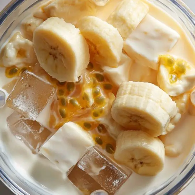 Blender filled with passionfruit smoothie ingredients on a counter