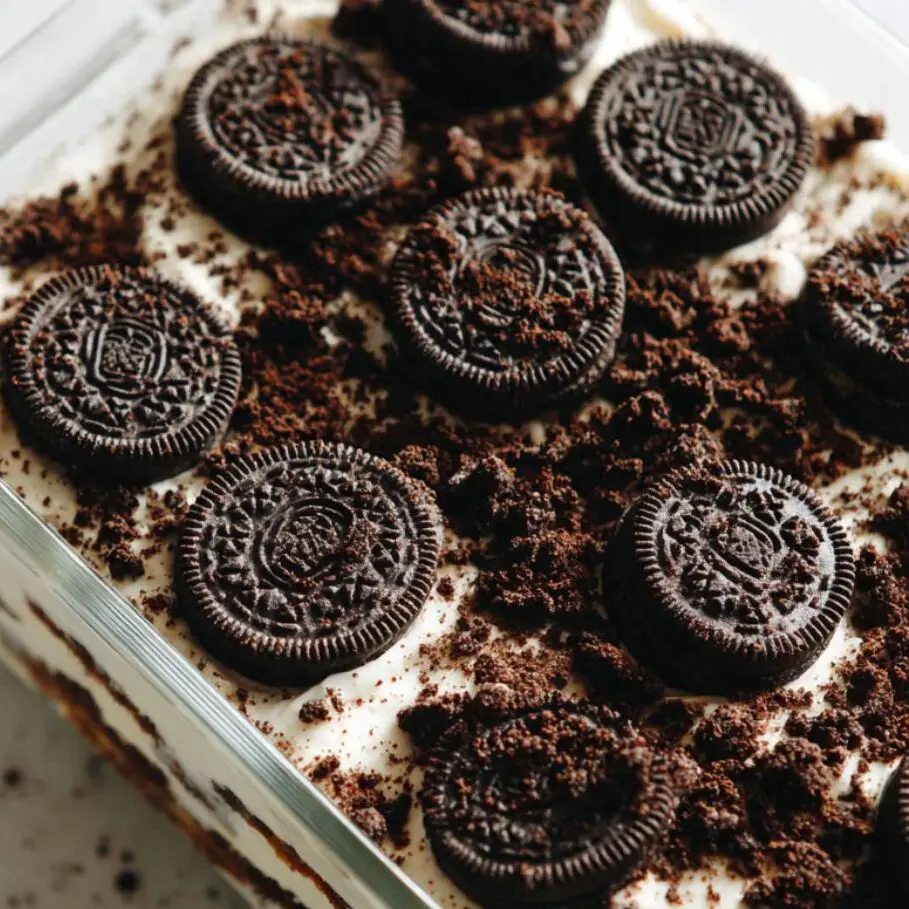 Layer of Oreo cookies arranged in a dish with cream spread over