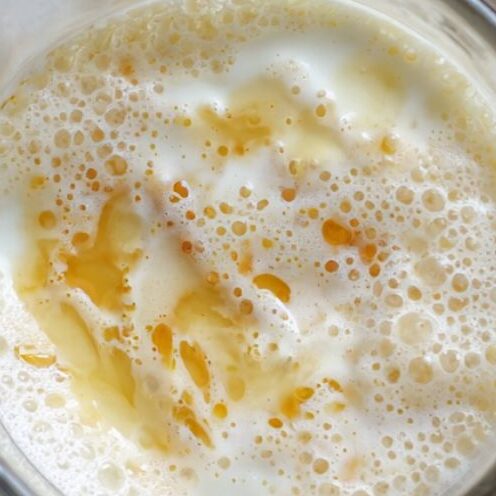 Blender filled with almond milk and yogurt on a white countertop