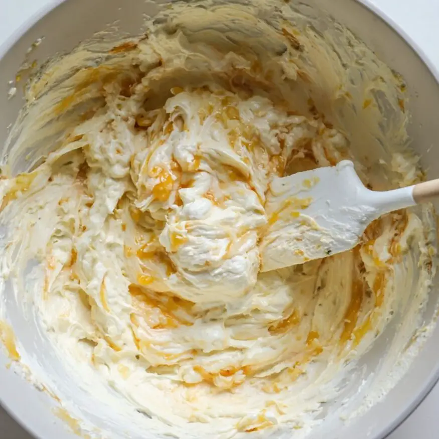 Creamy cheesecake filling being mixed in a bowl on a counter

