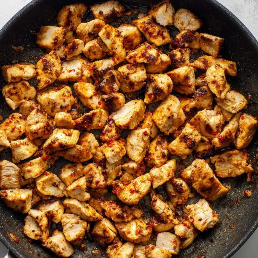 Chicken cooking in skillet with char marks