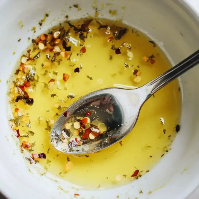 Citrus chili dressing stirred in a small bowl on a white kitchen counter

