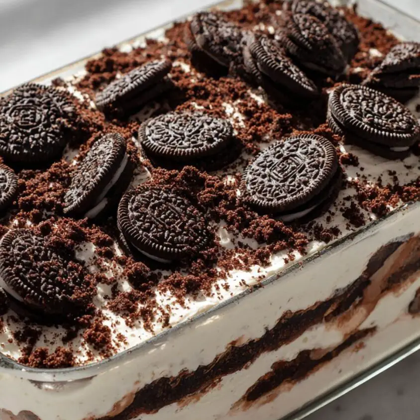 Oreo and cream layers being stacked in a glass dish