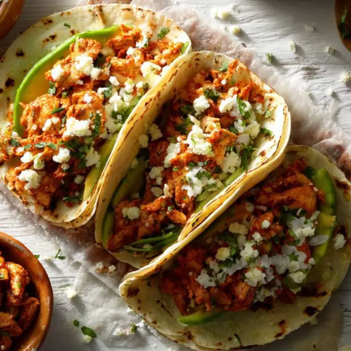 Assembling spicy chicken tacos with toppings