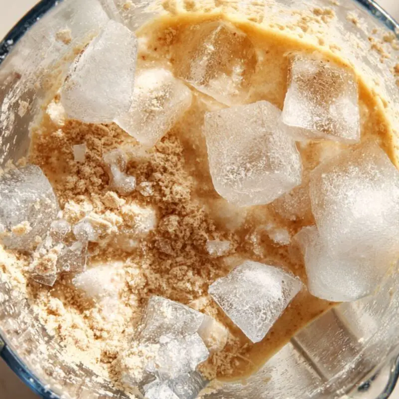 Guava smoothie being blended with ice cubes

