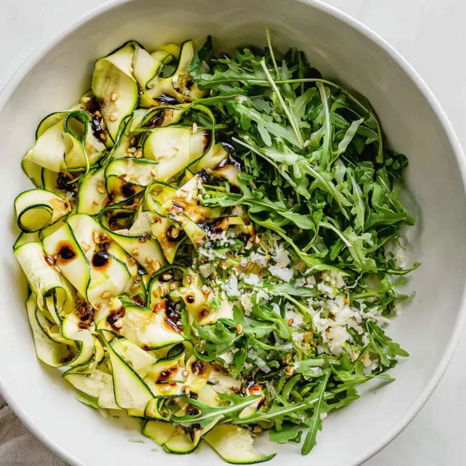 Assembled zucchini ribbon salad with fresh toppings in a serving bowl