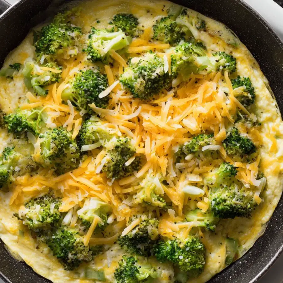 Cheddar and broccoli filling on one half of the omelette in the pan.