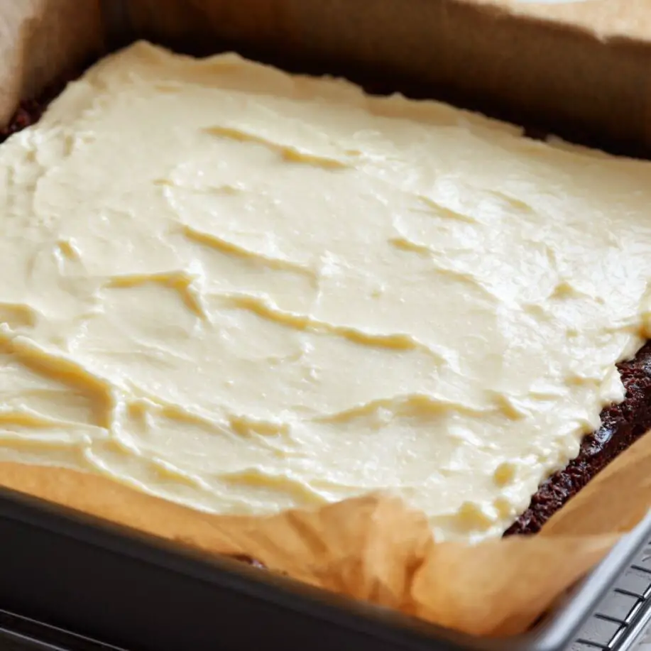 Freshly baked brownie bottom cheesecake cooling on a rack.