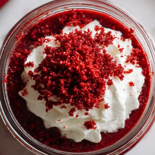 Chilled red velvet pudding served with whipped cream and red velvet crumbs
