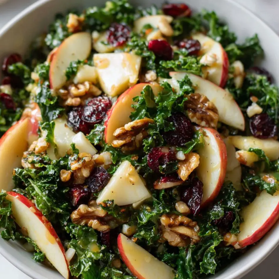 Apple Walnut Kale Salad being tossed together in a large bowl.