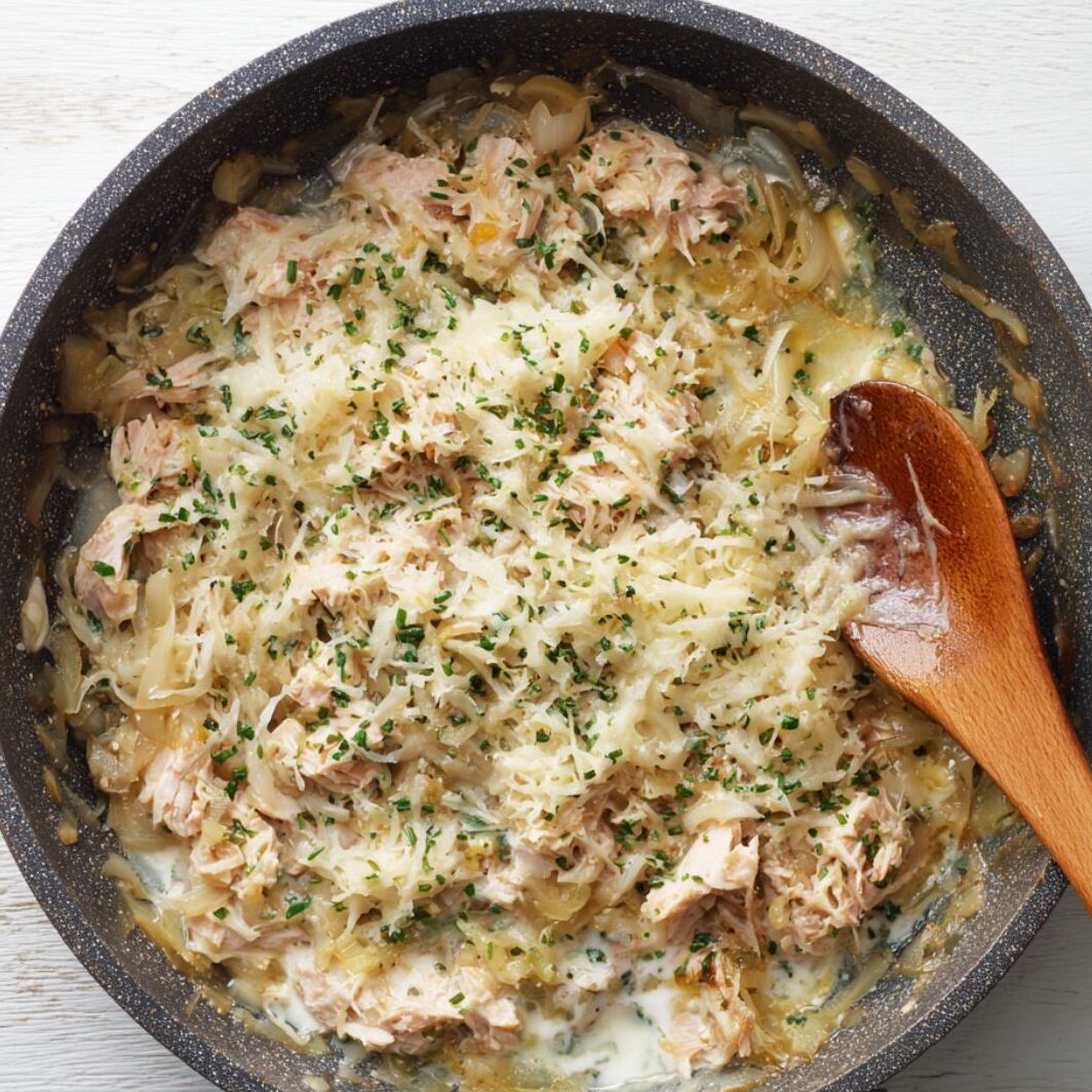 Creamy tuna sauce with onions and melted cheese in a skillet