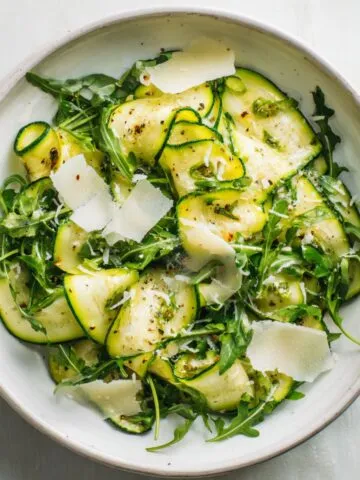 Fresh zucchini ribbon salad recipe with lemon and parmesan on white kitchen counter