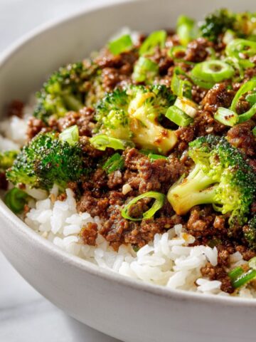 Overhead shot of a homemade beef bowl recipe with ground beef, rice, and vegetables served in a white bowl on a white kitchen counter.