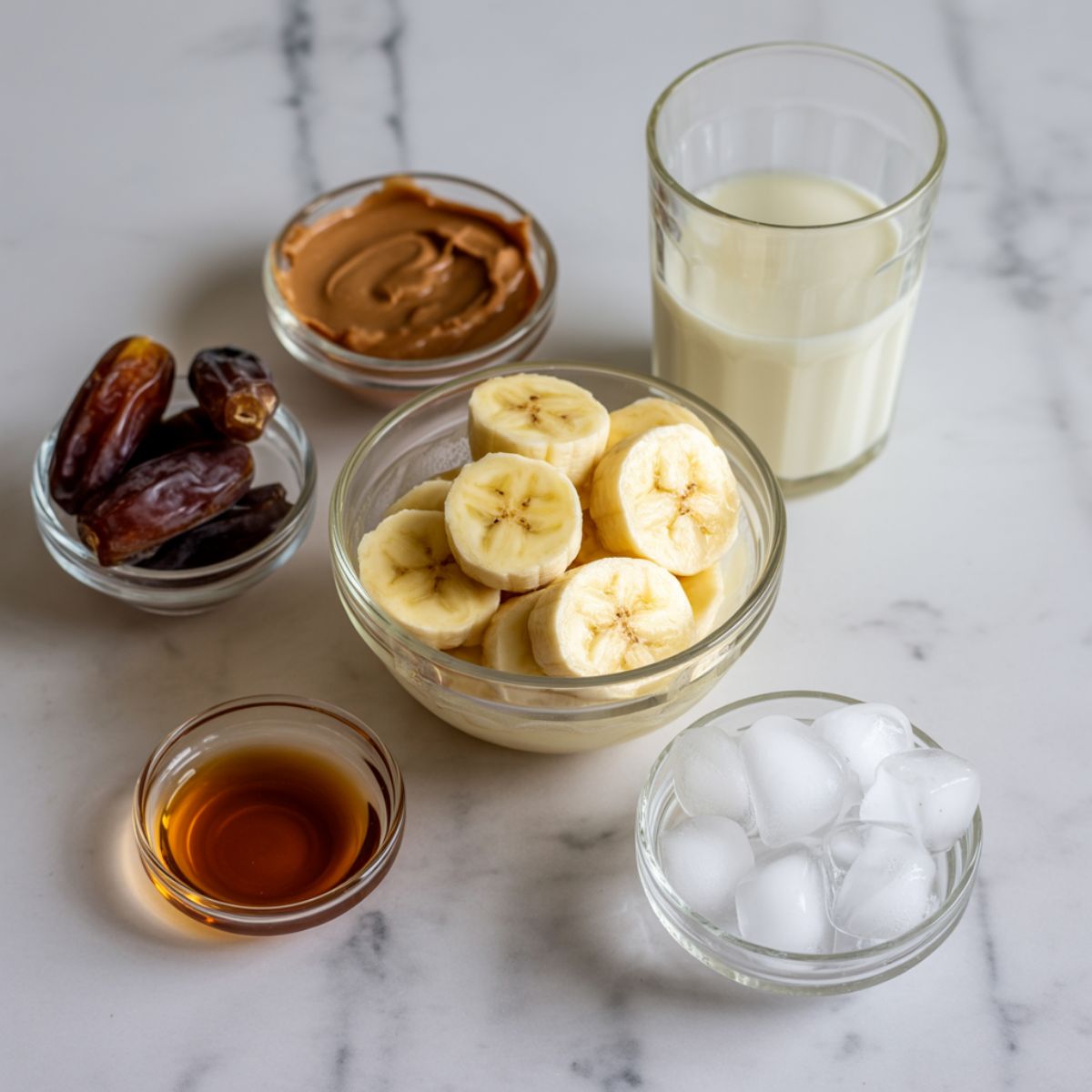 Caramel smoothie ingredients laid out on a white marble kitchen counter