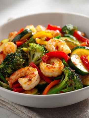 Homemade Shrimp Stir Fry with Veggies Recipe with colorful vegetables in a white bowl, photographed from above on a white kitchen counter.