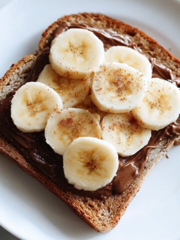 Homemade Nutella and banana toast recipe stacked on a white plate taken from above
