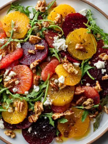 Overhead view of vibrant citrus beet salad with goat cheese recipe and nuts on a white kitchen counter