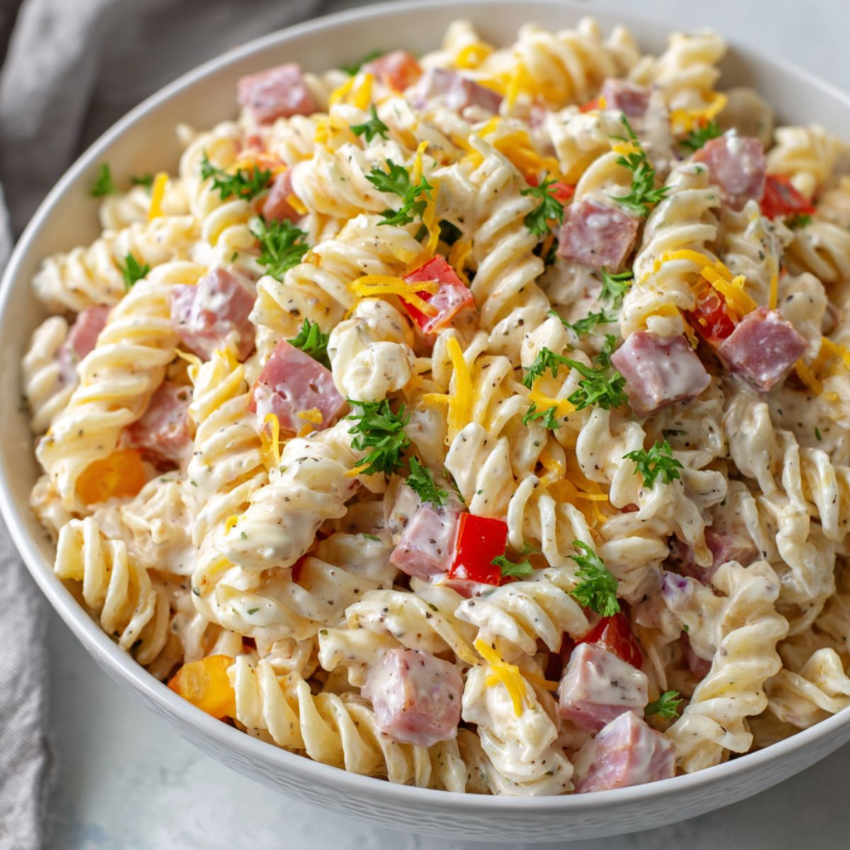 Overhead view of homemade ham and cheese pasta salad recipe in a large white bowl