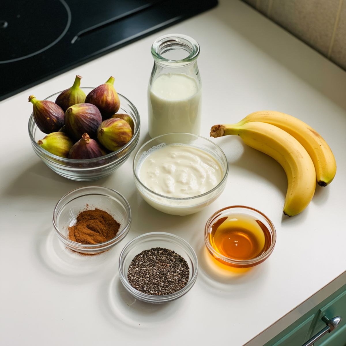 Fresh figs, banana, almond milk, yogurt, and cinnamon arranged on a white counter