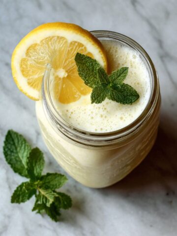 Overhead shot of a homemade lemon ginger smoothie recipe in a mason jar with lemon slice and mint