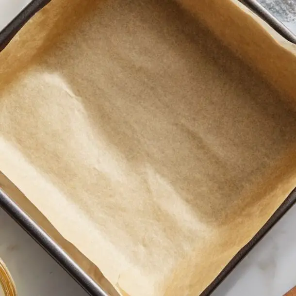 Overhead view of lined baking pan and butter-sugar mixture for coconut brownies

